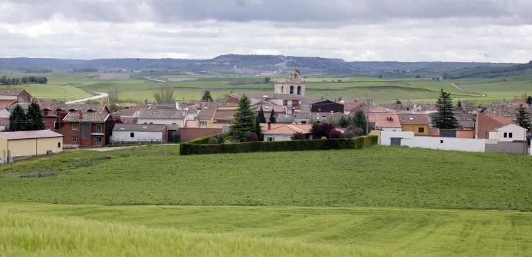 Panorámica de la vega verde con el pueblo al fondo