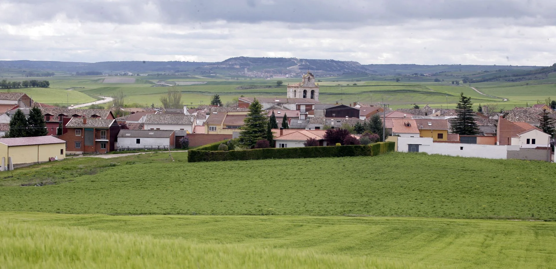 Panorámica de la vega verde con el pueblo al fondo